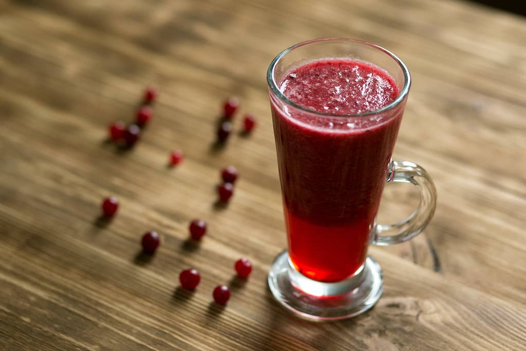 glass mug with red juice on wooden table