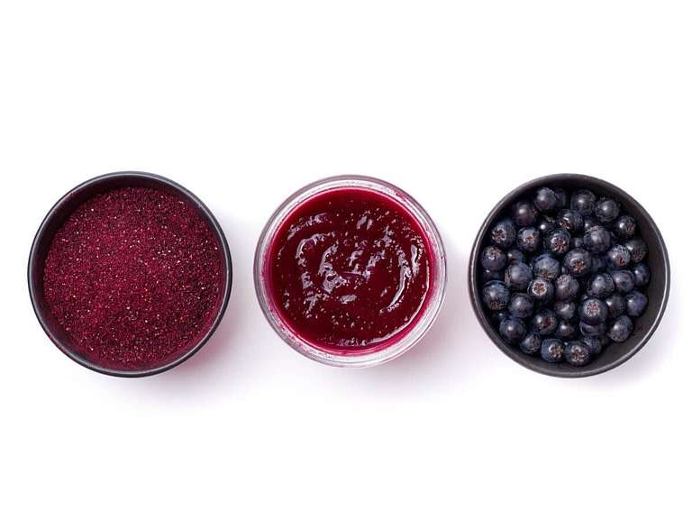 Aronia powder, jam and fresh berries in bowls